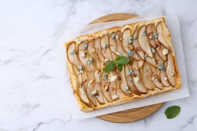 Delicious puff pastry tart with pears, almond, mint and blue cheese on white marble table, top view. Space for text