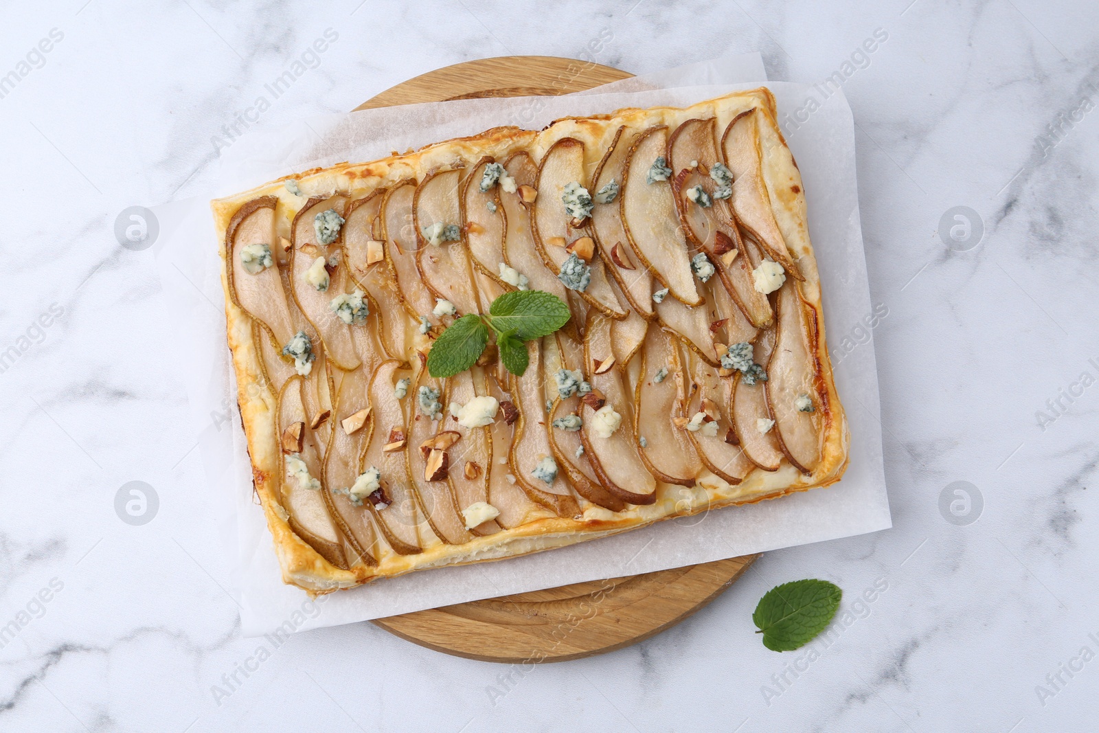 Photo of Delicious puff pastry tart with pears, almond, mint and blue cheese on white marble table, top view