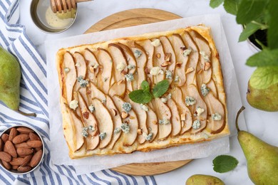 Photo of Delicious puff pastry tart with pears, almond, mint and blue cheese on light table, flat lay