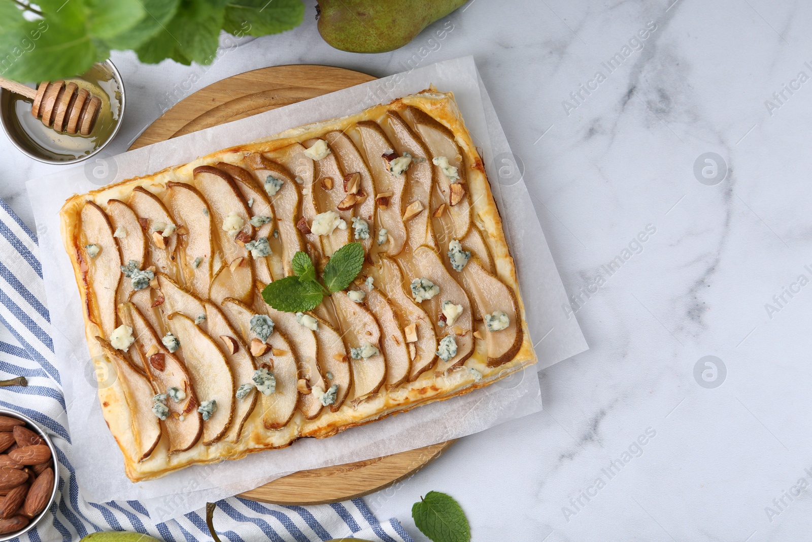 Photo of Delicious puff pastry tart with pears, almond, mint and blue cheese on white marble table, flat lay. Space for text