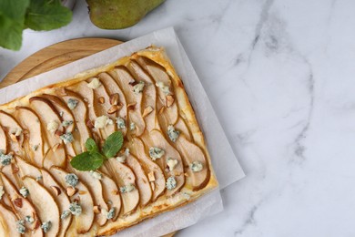 Delicious puff pastry tart with pears, almond, mint and blue cheese on white marble table, flat lay. Space for text