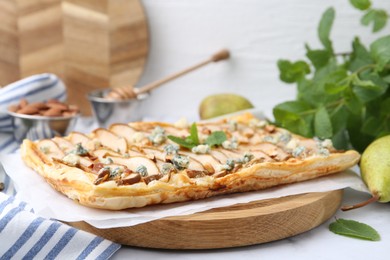 Delicious puff pastry tart with pears, almond, mint and blue cheese on white table, closeup