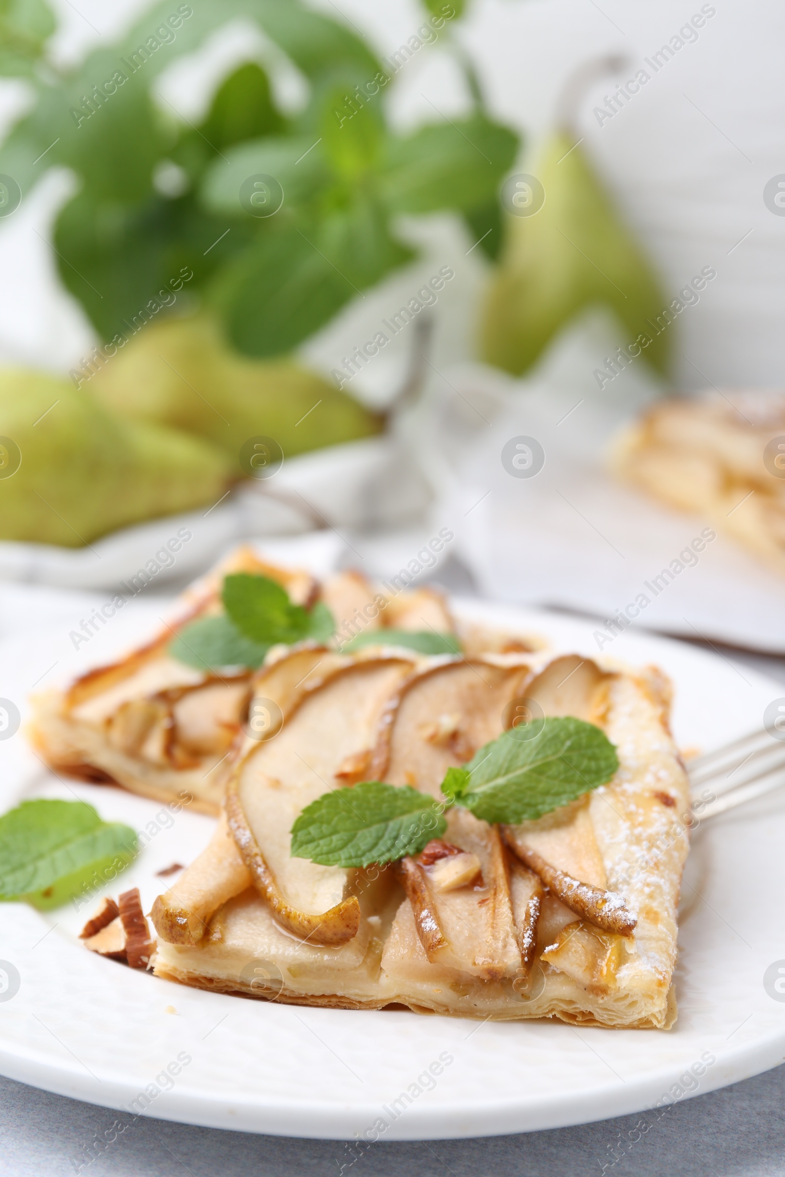 Photo of Pieces of tasty puff pastry pie with pears and mint on table, closeup