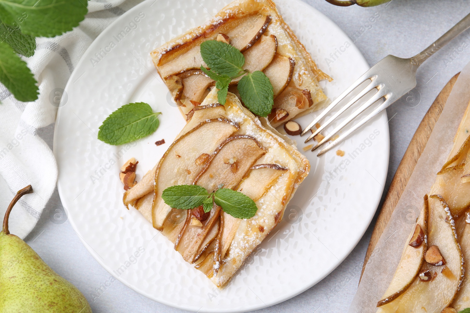 Photo of Pieces of tasty puff pastry pie with pears and mint on light grey table, top view