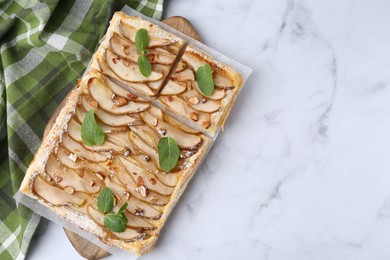 Tasty puff pastry pie with pears and mint on white marble table, top view. Space for text