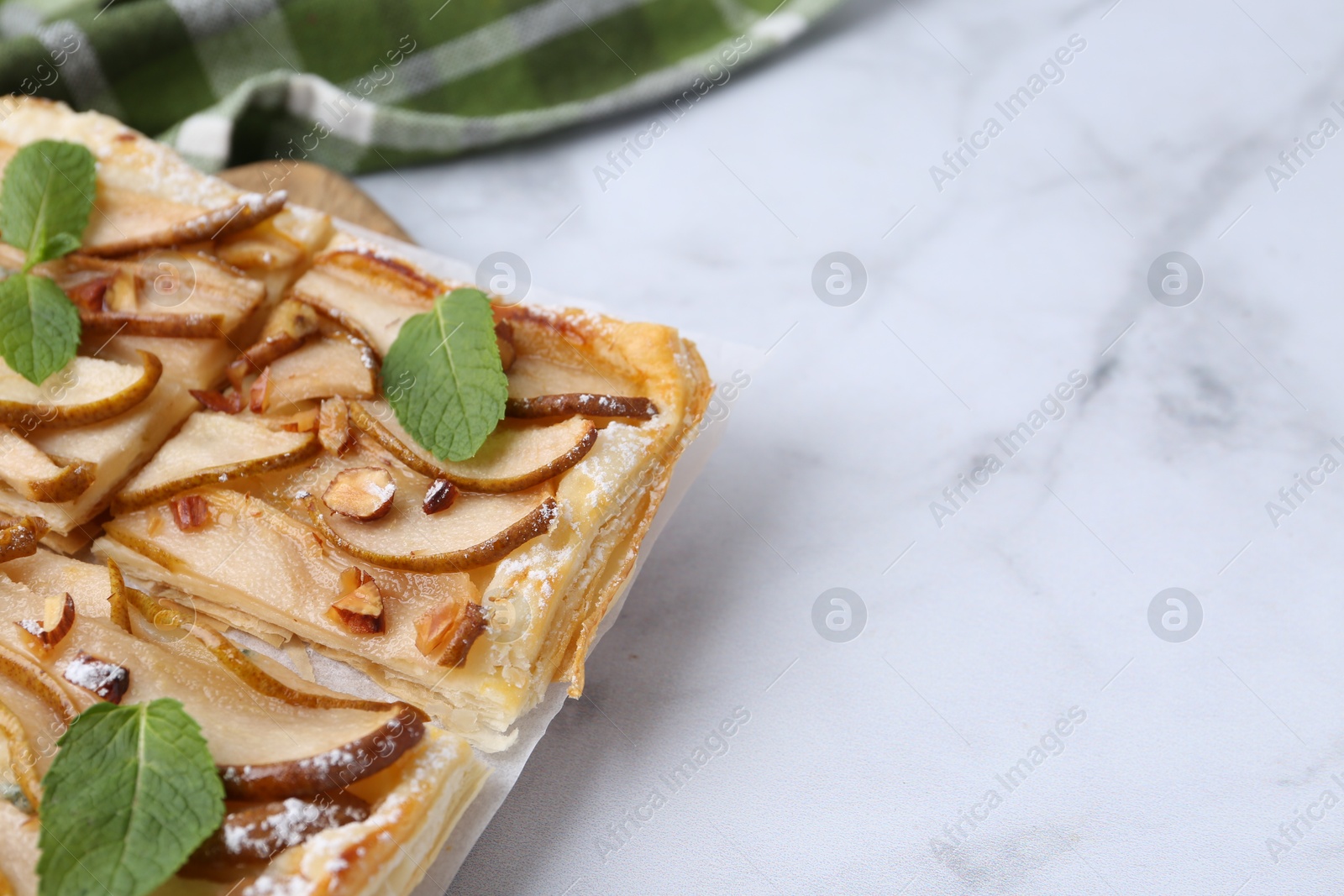 Photo of Tasty puff pastry pie with pears and mint on white marble table, closeup. Space for text