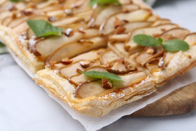 Photo of Tasty puff pastry pie with pears and mint on white table, closeup