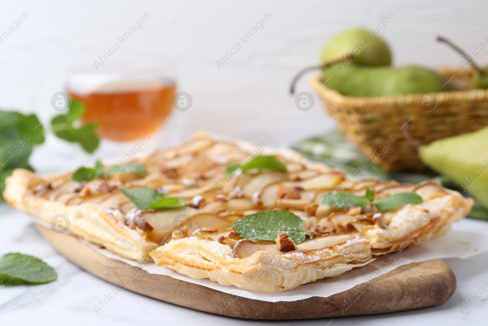 Photo of Tasty puff pastry pie with pears and mint on white table, closeup