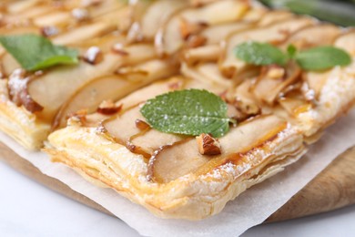 Photo of Tasty puff pastry pie with pears and mint on table, closeup