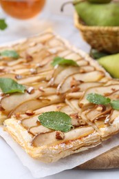 Tasty puff pastry pie with pears and mint on table, closeup