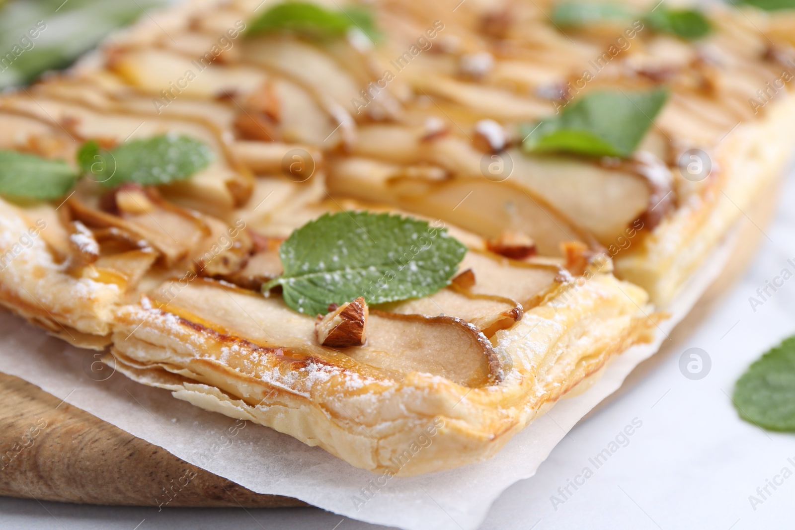 Photo of Tasty puff pastry pie with pears and mint on white table, closeup