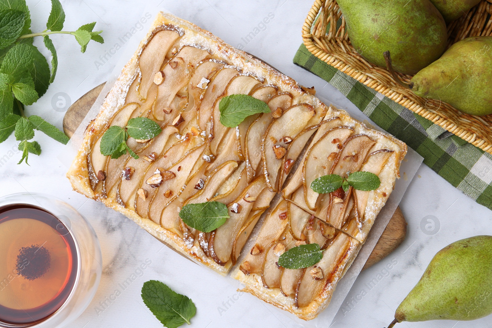 Photo of Tasty puff pastry pie with pears, mint and tea on white marble table, top view