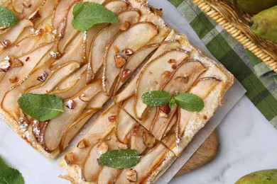 Tasty puff pastry pie with pears and mint on white marble table, top view