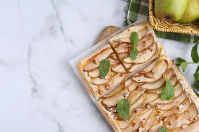 Photo of Tasty puff pastry pie with pears and mint on white marble table, top view. Space for text