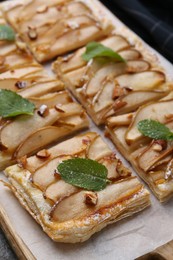 Photo of Tasty puff pastry pie with pears and mint on table, closeup