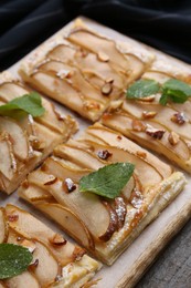 Photo of Tasty puff pastry pie with pears and mint on table, closeup