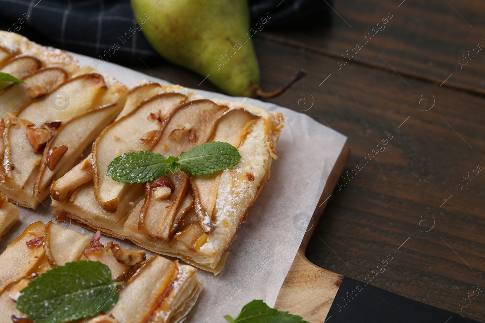 Photo of Tasty puff pastry pie with pears and mint on wooden table, closeup