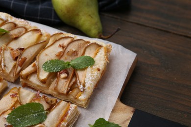 Photo of Tasty puff pastry pie with pears and mint on wooden table, closeup