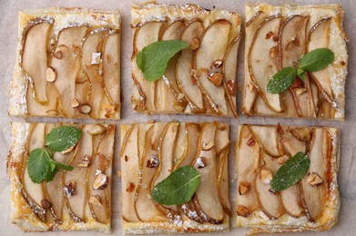 Photo of Tasty puff pastry pie with pears and mint on parchment paper, top view