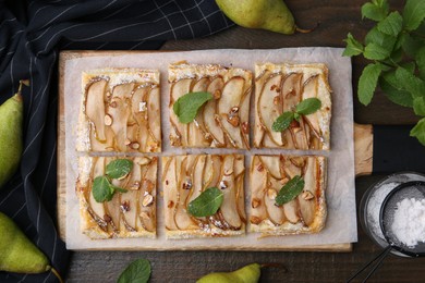 Photo of Tasty puff pastry pie with pears, mint and powdered sugar on wooden table, top view