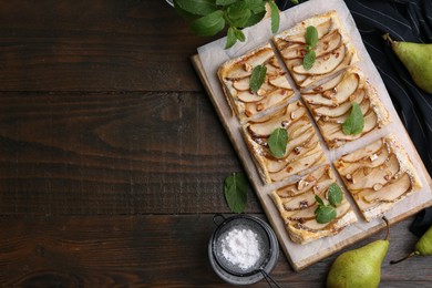 Tasty puff pastry pie with pears, mint and powdered sugar on wooden table, top view. Space for text