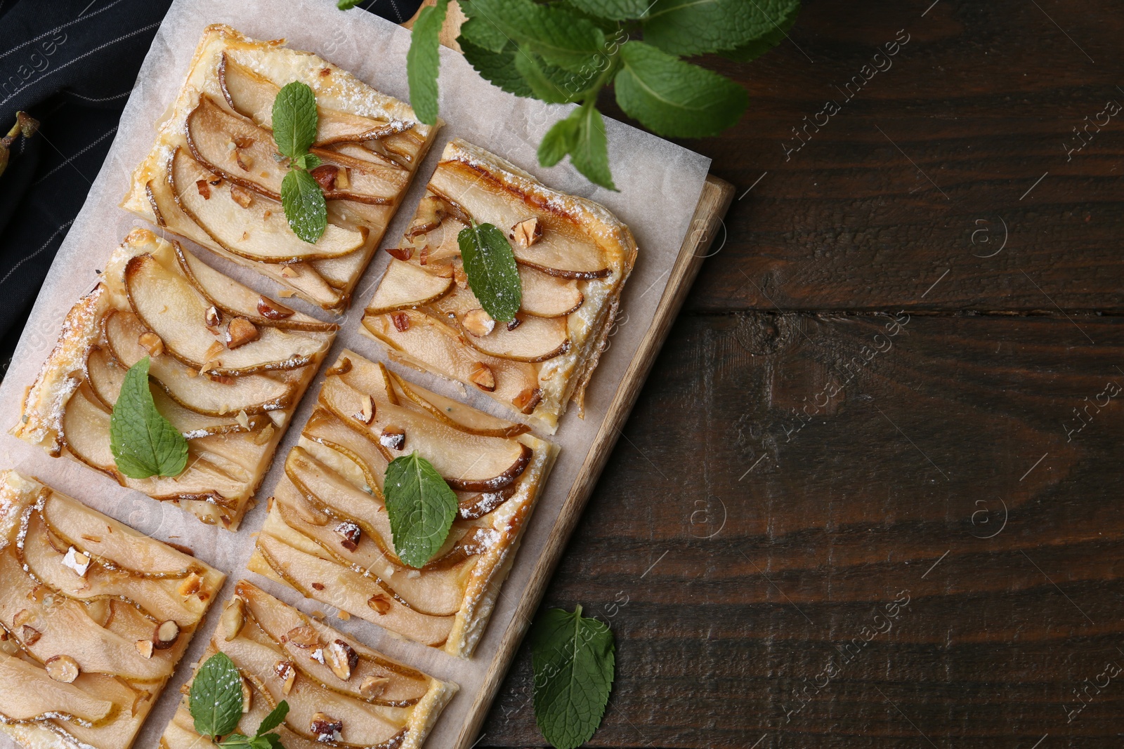 Photo of Tasty puff pastry pie with pears and mint on wooden table, top view. Space for text