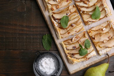 Photo of Tasty puff pastry pie with pears, mint and powdered sugar on wooden table, top view. Space for text