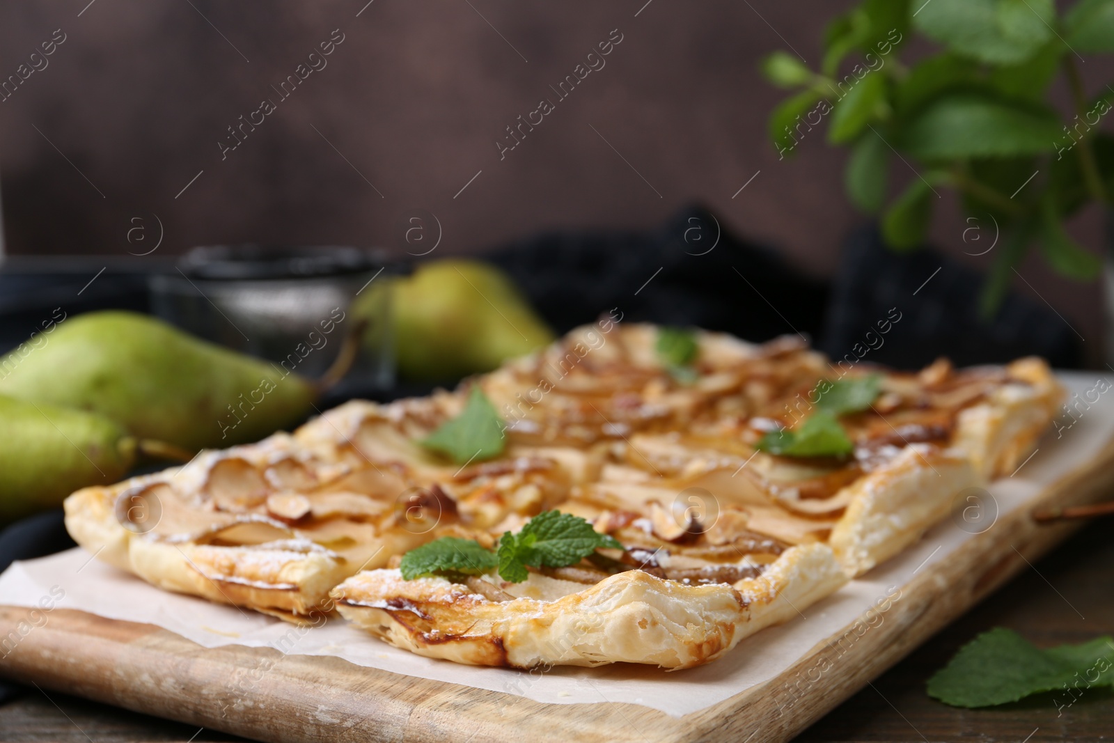 Photo of Tasty puff pastry pie with pears and mint on table, closeup