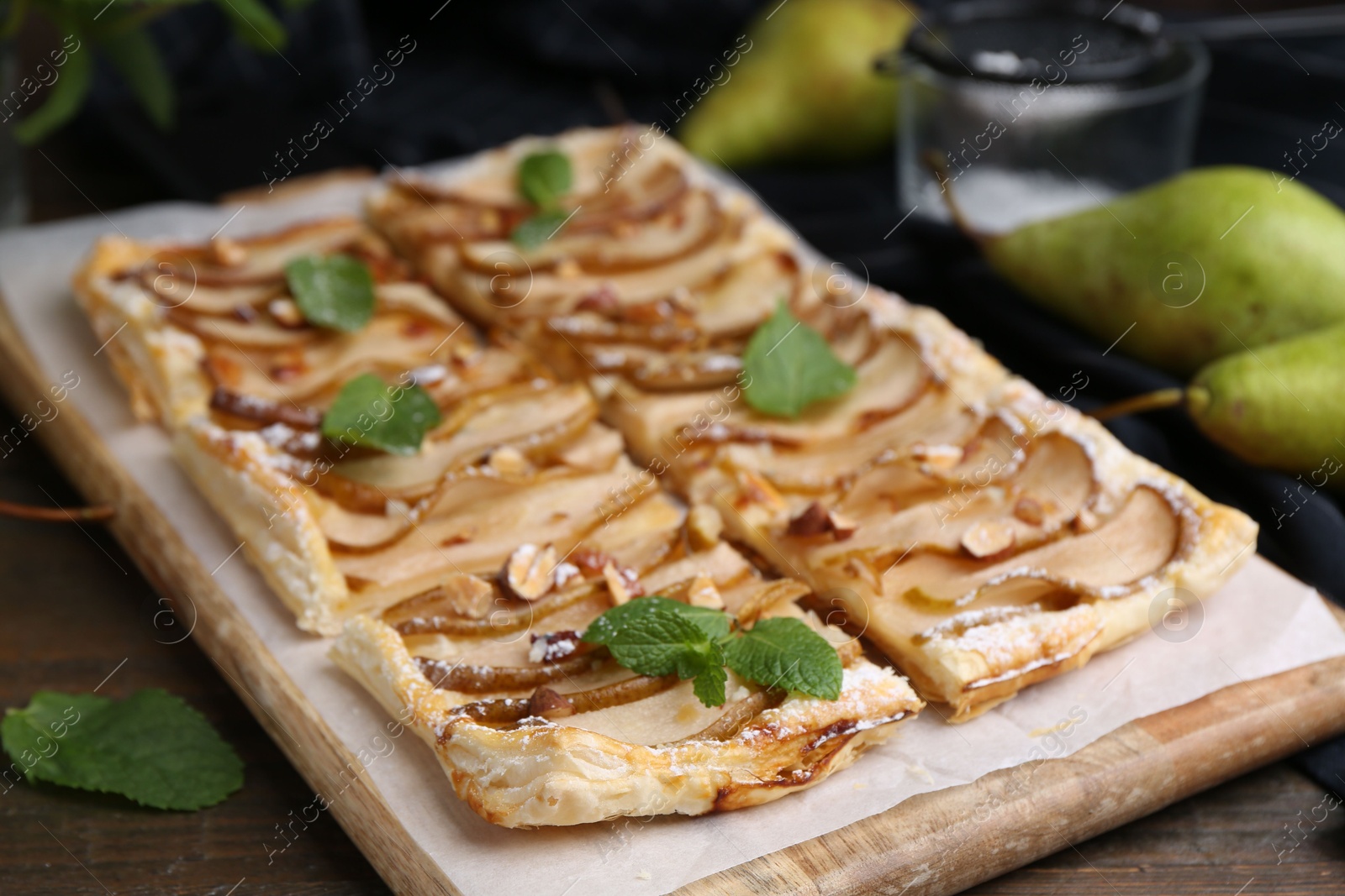 Photo of Tasty puff pastry pie with pears and mint on wooden table, closeup