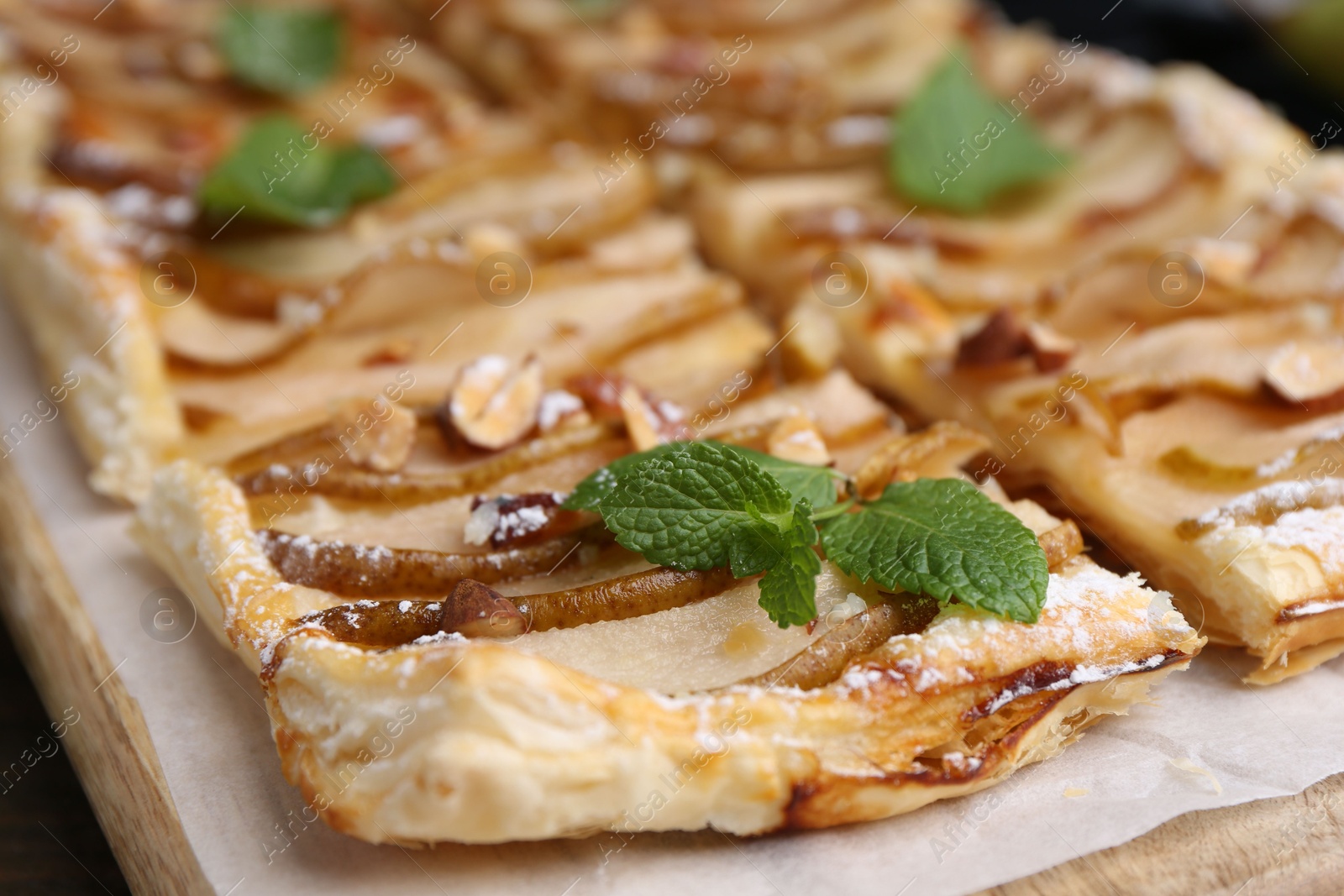 Photo of Tasty puff pastry pie with pears and mint on table, closeup