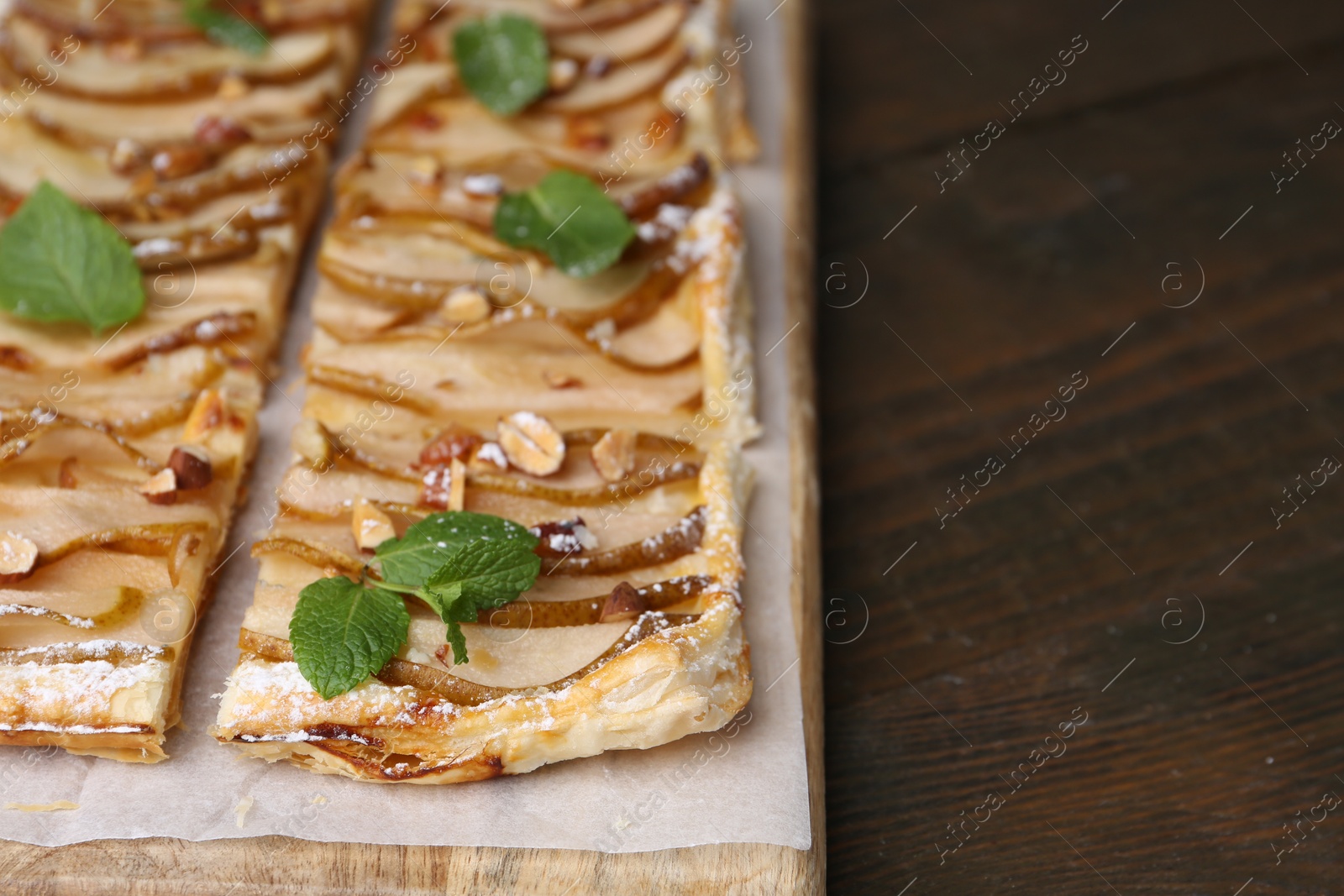 Photo of Tasty puff pastry pie with pears and mint on wooden table, closeup. Space for text