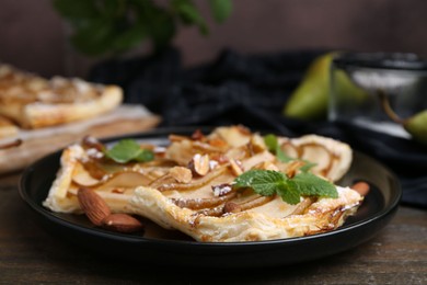 Photo of Pieces of tasty puff pastry pie with pears, mint and almonds on wooden table, closeup