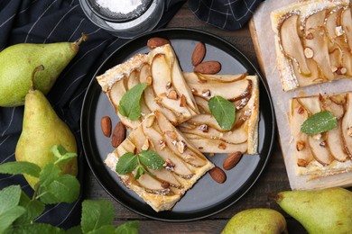 Photo of Pieces of tasty puff pastry pie with pears, mint and almonds on wooden table, top view