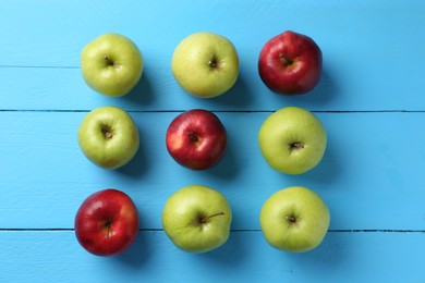 Photo of Fresh red and green apples on light blue wooden table, flat lay