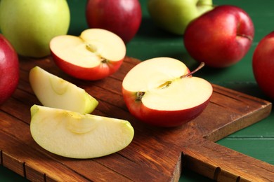 Photo of Fresh ripe apples on green wooden table, closeup