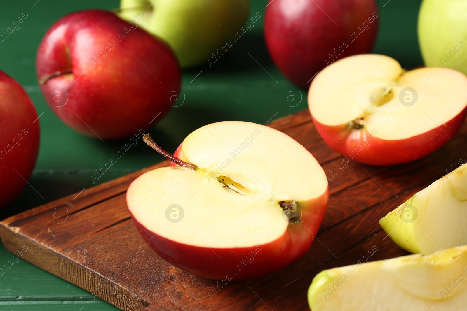 Photo of Fresh ripe apples on green wooden table, closeup