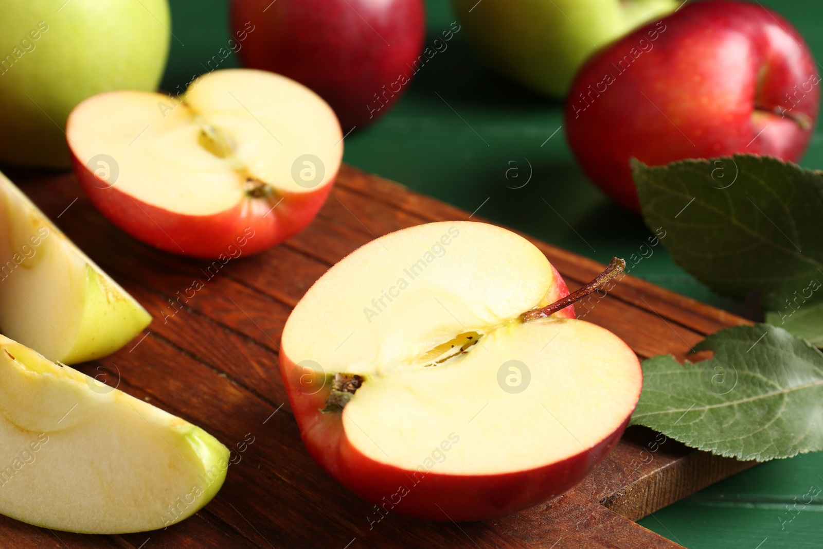 Photo of Fresh ripe apples on green wooden table, closeup