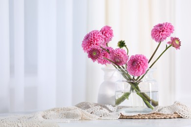 Photo of Beautiful pink flowers in vase on table indoors. Space for text