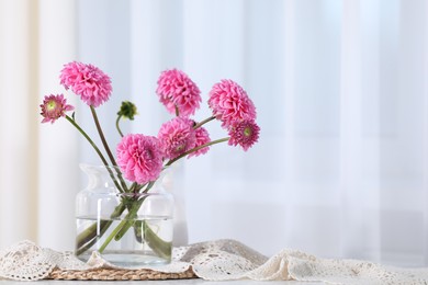 Photo of Beautiful pink flowers in vase on table indoors. Space for text