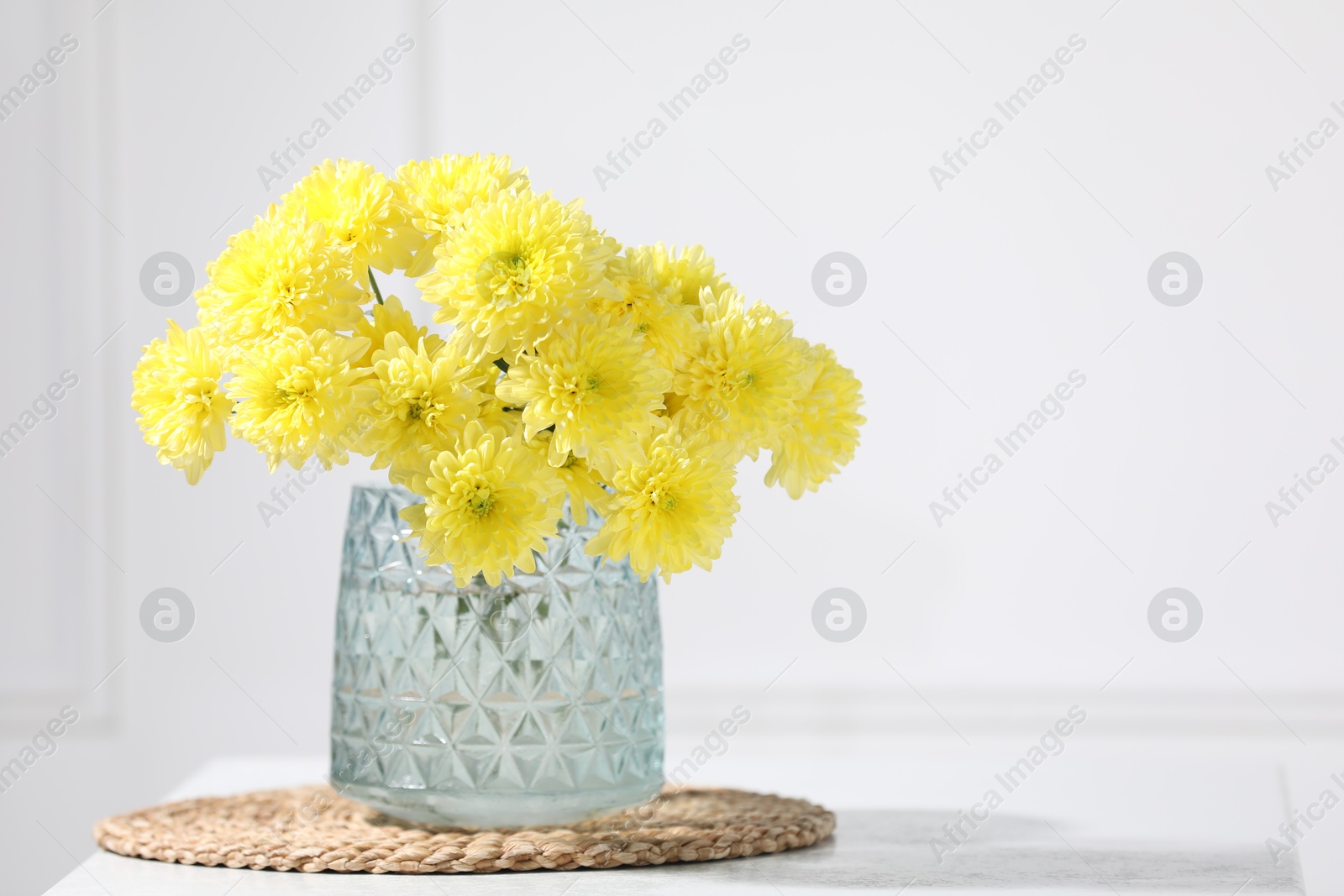 Beautiful yellow flowers in vase on table indoors. Space for text Photo of Beautiful yellow flowers in vase on table indoors. Space for text