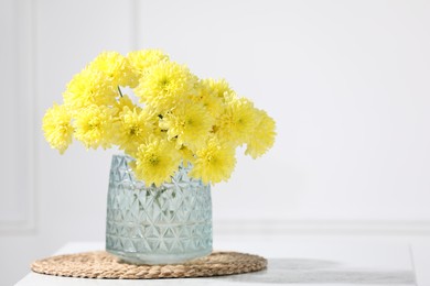 Photo of Beautiful yellow flowers in vase on table indoors. Space for text