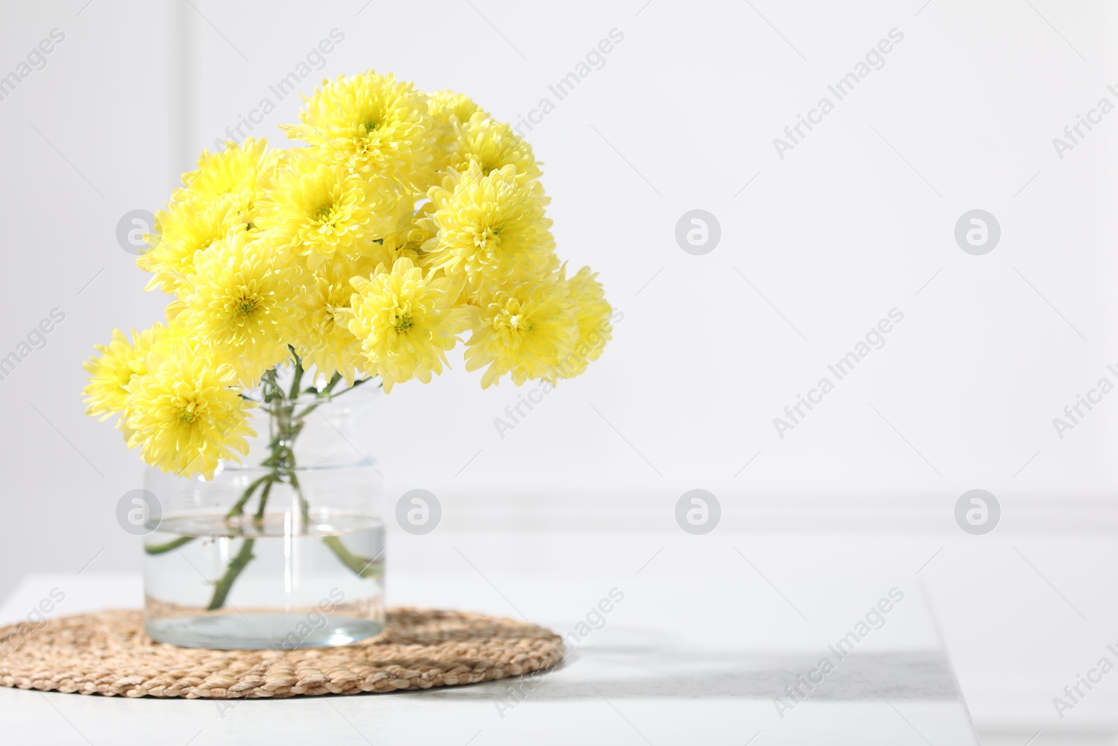 Beautiful yellow flowers in vase on table indoors. Space for text Photo of Beautiful yellow flowers in vase on table indoors. Space for text