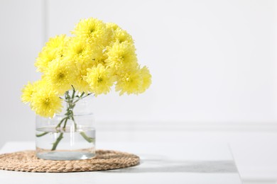 Photo of Beautiful yellow flowers in vase on table indoors. Space for text