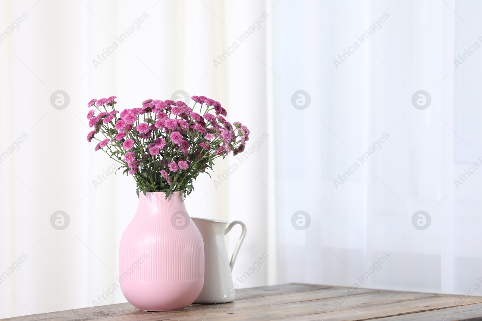 Beautiful pink flowers in vase on wooden table indoors. Space for text Photo of Beautiful pink flowers in vase on wooden table indoors. Space for text
