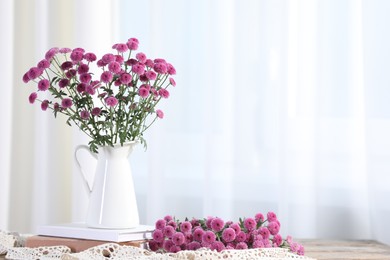 Photo of Beautiful chrysanthemum flowers and books on table indoors. Space for text