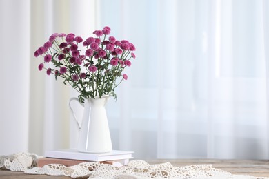 Photo of Beautiful pink flowers in vase and books on table indoors, space for text