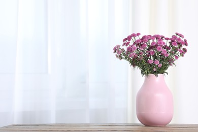 Photo of Beautiful pink flowers in vase on table indoors. Space for text