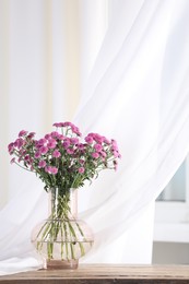 Photo of Beautiful pink flowers in vase on table indoors. Space for text