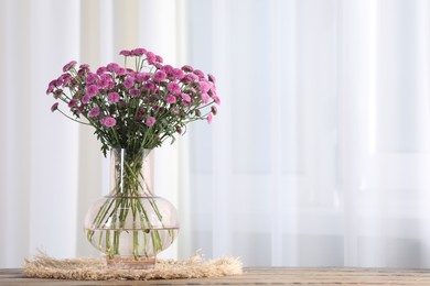 Photo of Beautiful pink flowers in vase on table indoors. Space for text