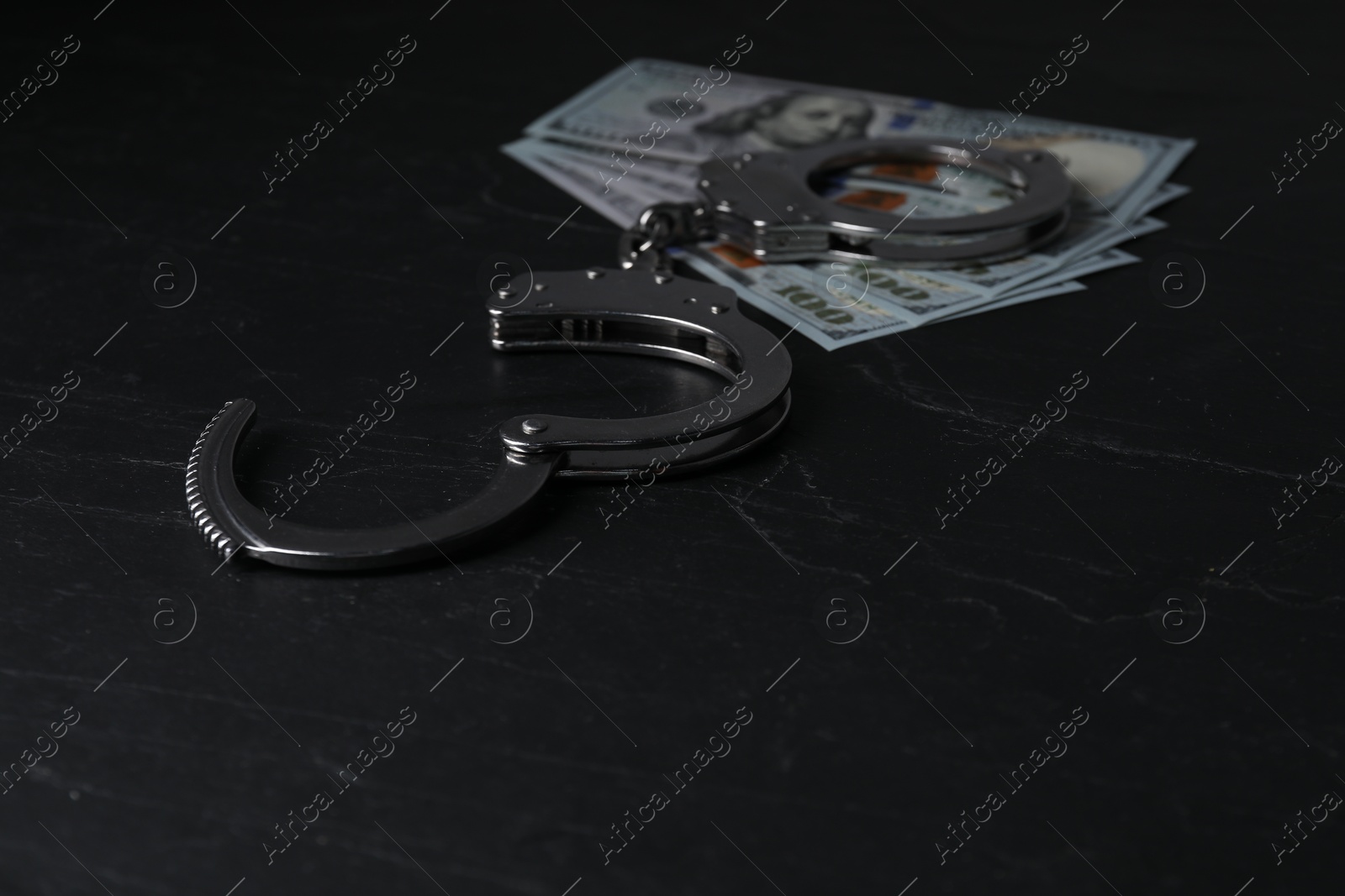 Photo of Corruption. Dollar banknotes and handcuffs on black table